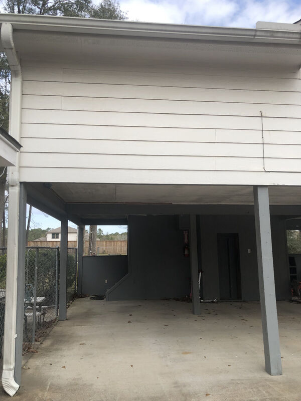 Open carport bay beneath a raised house before enclosure