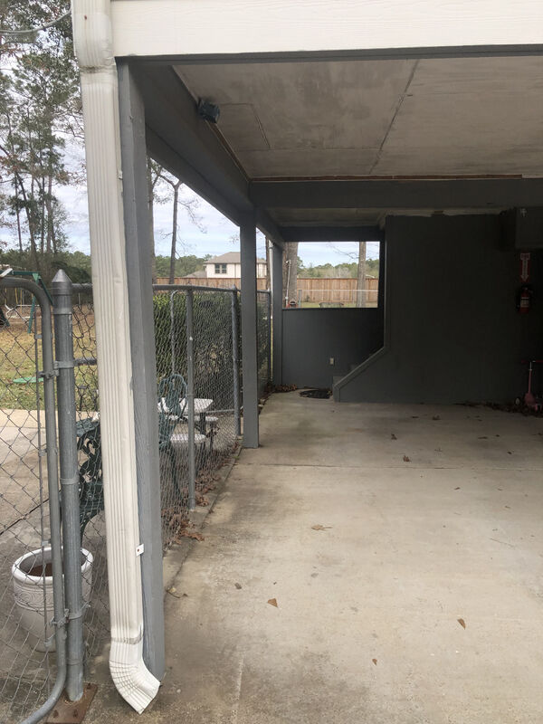 Looking through the open carport bay toward the driveway before enclosure
