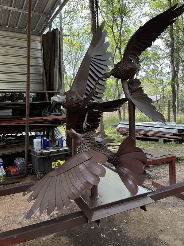 Two metal eagle sculptures with outstretched wings mounted on a steel base
