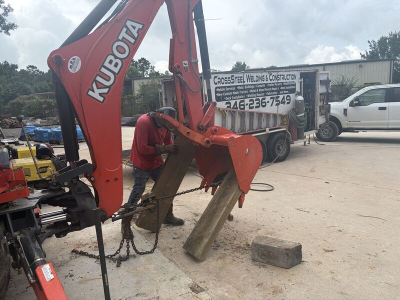 Red excavator with its bucket detached during a field repair call